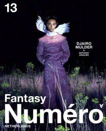 Model Djairo Mulder wearing a patterned purple suit with white wing-like collar details standing in a field at night for Numéro Netherlands.