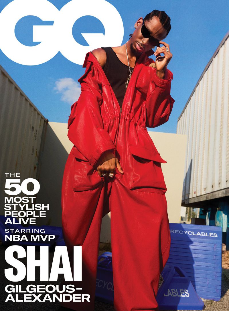 GQ magazine cover featuring an adult Black male wearing a red coat and pants, sunglasses, and jewelry against a blue sky backdrop.