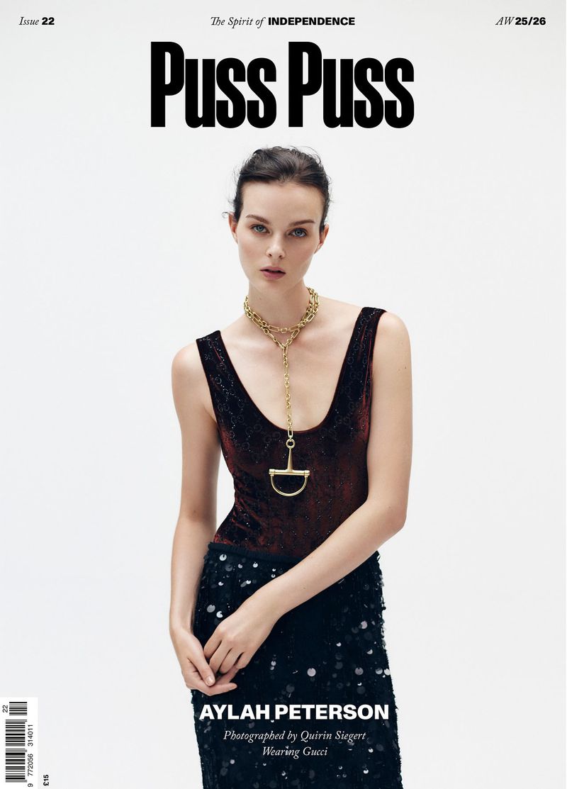 Magazine cover featuring a woman with dark hair wearing a dark top and long skirt with a gold necklace on a white background.