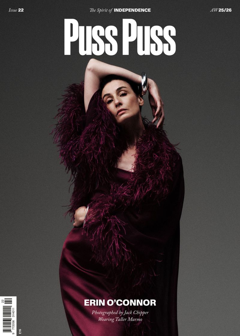 Magazine cover featuring Erin O'Connor in a maroon dress with feathered trim, posing against a grey background. The magazine title is 'Puss Puss'.