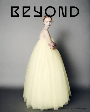 Model Ella Dalton posing in a voluminous pale yellow strapless tulle ballgown against a neutral grey studio backdrop.