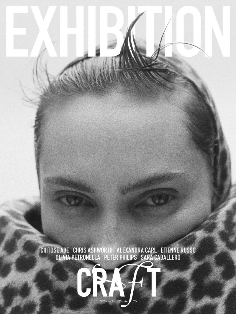 Monochrome portrait of a woman with wet hair and a patterned scarf, featuring exhibition text and designer names in a high-contrast image.