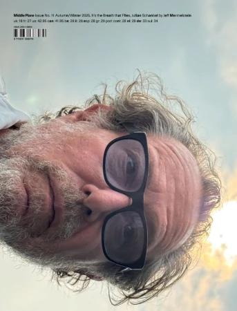 Magazine cover featuring an adult male with glasses against a sky backdrop. The image has an artistic, editorial style.