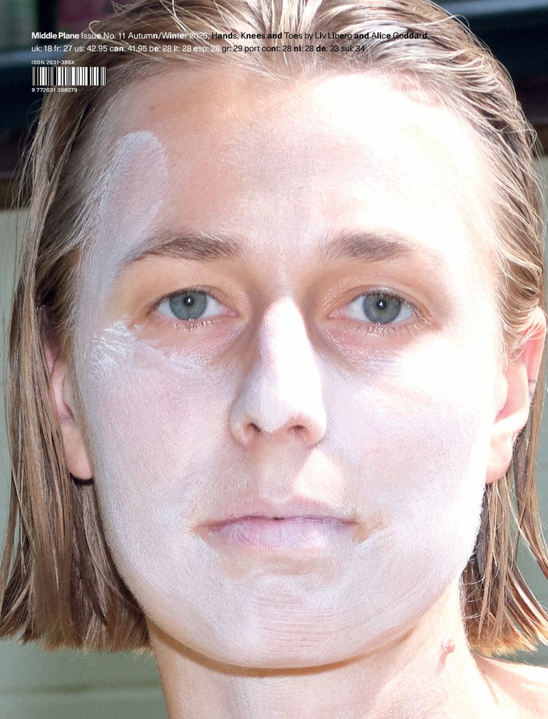 Close-up portrait of an adult female with short blond hair, wearing white cream or cosmetic product on her face. Outdoor setting.