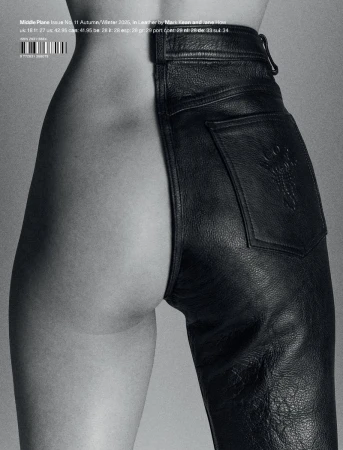 Close-up of a model wearing split black leather trousers against a neutral grey studio background
