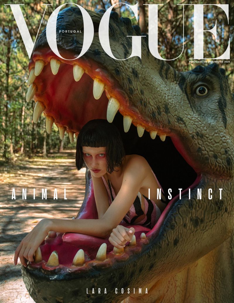 Vogue Portugal cover featuring a female model partially inside a dinosaur head, outdoors in a forest setting.