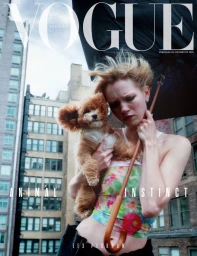 Model Lex Peckham holding a small fluffy dog under a black umbrella in front of city buildings for Vogue Portugal.