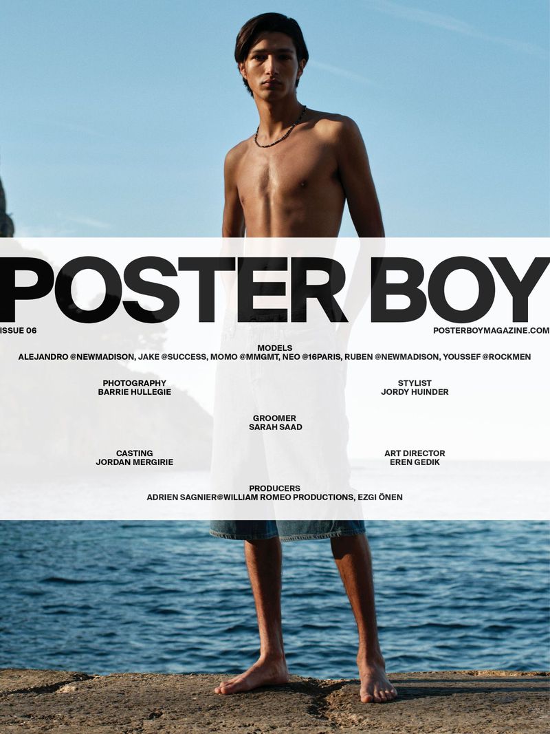 Shirtless male model poses on rocky shoreline for a magazine cover; blue sky and ocean are in the background.