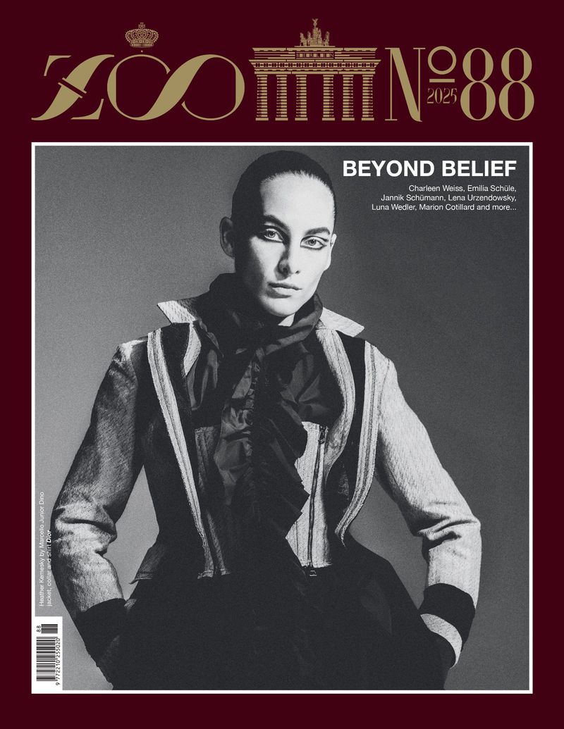 Monochromatic fashion magazine cover featuring a portrait of a model in a structured jacket and ruffled top against a studio backdrop.