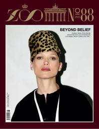 Model Hana Jirickova wearing a leopard print tall hat and black cape against a pale studio wall on the cover of Zoo Magazine.