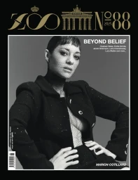 Monochrome magazine cover portrait of Marion Cotillard wearing a dark jacket over sheer mesh netting against a grey studio backdrop.
