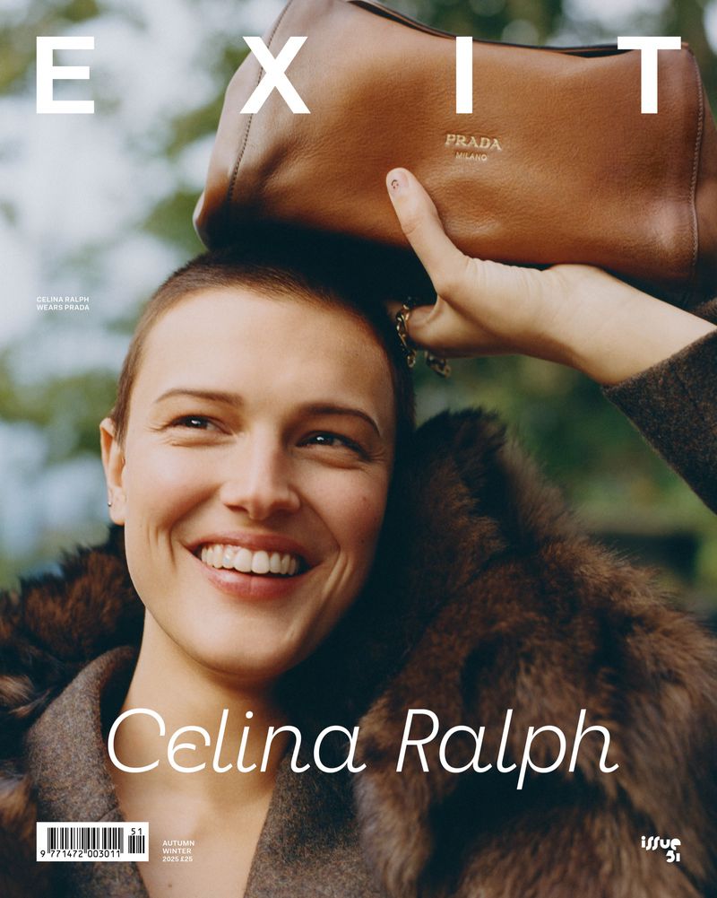 Magazine cover featuring a smiling woman wearing a fur coat and a brown Prada handbag in an outdoor setting with green background.