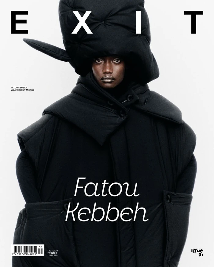 Model Fatou Kebbeh wearing an oversized sculptural black puffer headpiece and coat against a white backdrop for Exit Magazine.