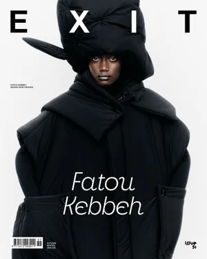 Model Fatou Kebbeh wearing an oversized sculptural black puffer headpiece and coat against a white backdrop for Exit Magazine.