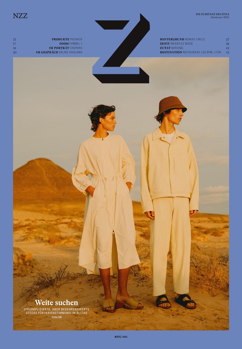 Fashion editorial cover with two neutral-toned models in a desert landscape wearing relaxed clothing, stylized under geometric text.