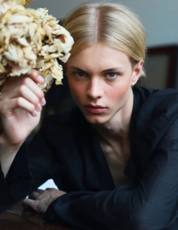 Blonde male model with blue eyes holding a bunch of dried flowers while wearing a black shirt for MMScene editorial.