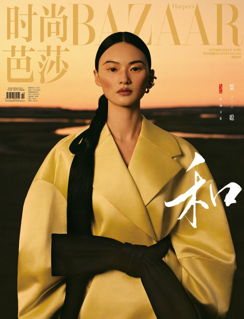 Magazine cover featuring an Asian woman wearing a yellow coat with a black belt, against a blurred landscape background with text.