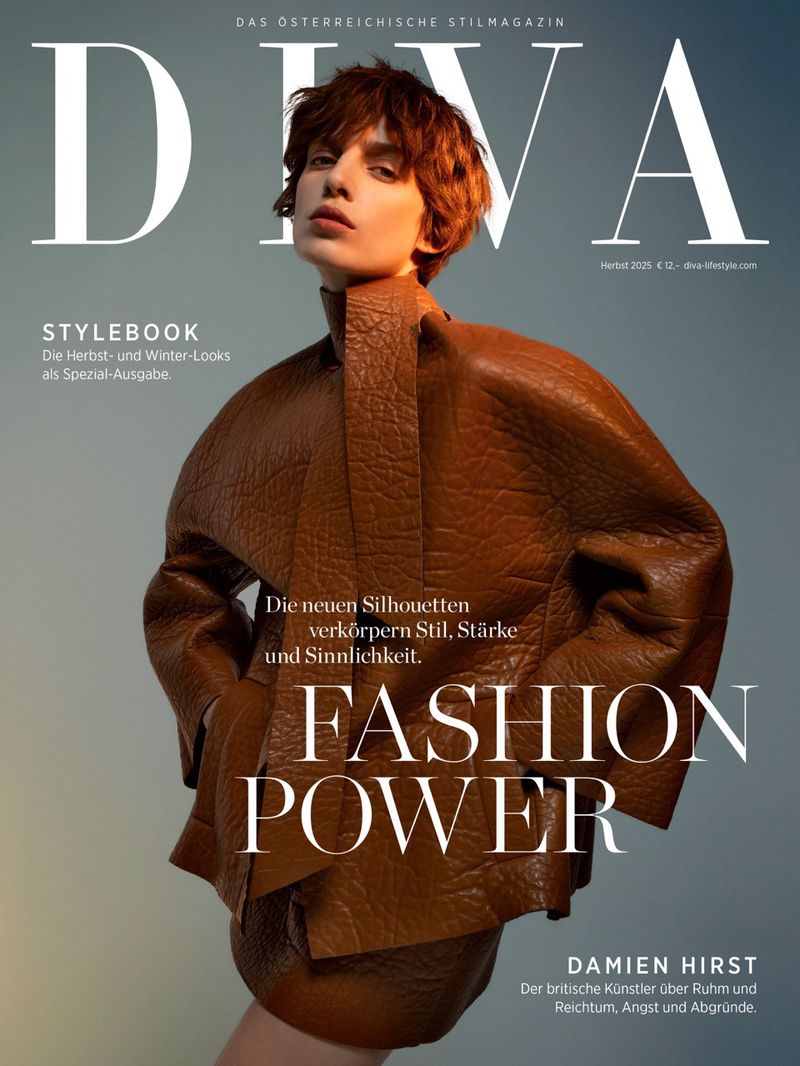 Fashion magazine cover featuring a person with auburn hair wearing a textured, brown leather-like outfit on a muted blue background.