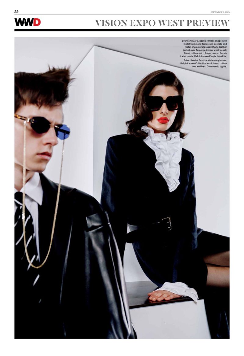 Editorial fashion shot featuring a male and female models wearing sunglasses, dark business suits, and standing against a white backdrop.