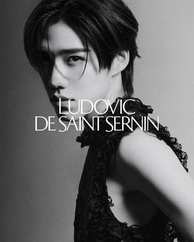 Portrait of a male fashion model wearing a black lace top, with a shallow depth of field and soft lighting, featuring the brand Ludovic de Saint Sernin.
