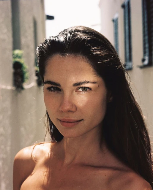 Portrait of a woman with brown hair in an outdoor setting with natural lighting, showcasing a minimalist aesthetic and focus on facial features.