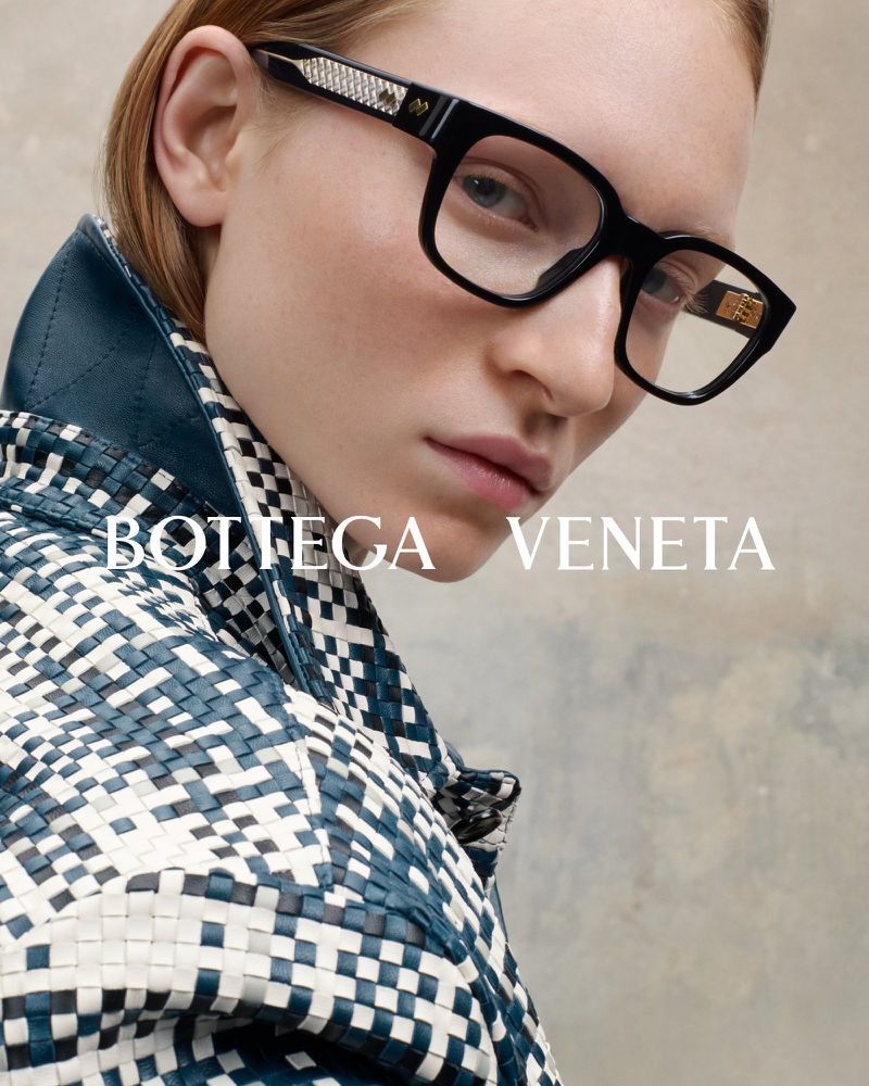 Fashion shot featuring a woman wearing Bottega Veneta eyeglasses with a woven blue and white jacket against a neutral backdrop.