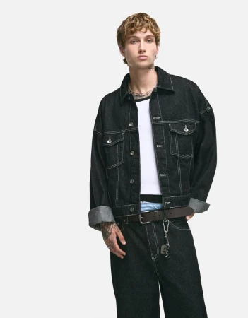 Young man wearing a black denim jacket and matching jeans over a white t-shirt against a plain white background.