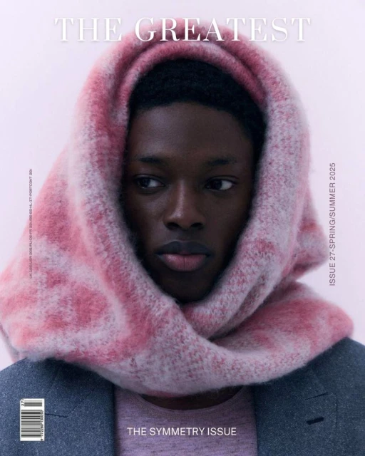 Magazine cover featuring a Black male model wearing a pink and white headscarf and a gray jacket on a light pink background.
