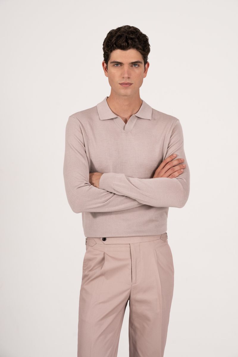 A light-skinned adult male model stands against a white backdrop, wearing a light-colored long-sleeve shirt and matching trousers with arms crossed.