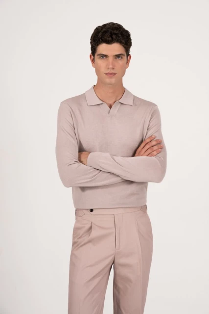 A light-skinned adult male model stands against a white backdrop, wearing a light-colored long-sleeve shirt and matching trousers with arms crossed.