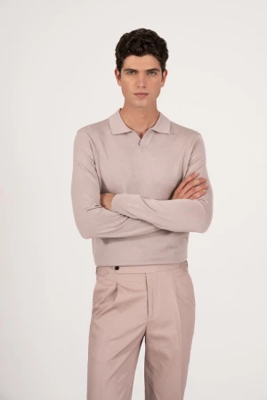 A light-skinned adult male model stands against a white backdrop, wearing a light-colored long-sleeve shirt and matching trousers with arms crossed.