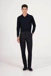 Male model wearing a dark polo shirt and trousers standing against a white seamless background