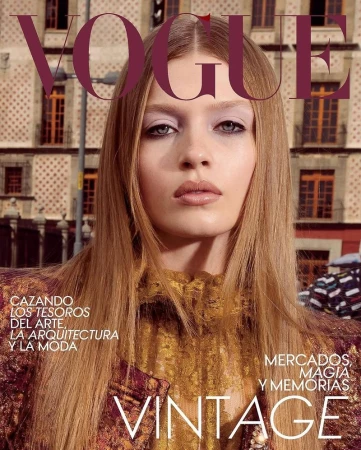 Vogue magazine cover featuring a close-up portrait of a blonde-haired model with a building facade as the background. Cover typography is visible.