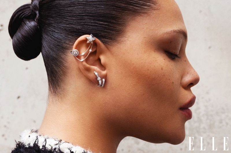 Close-up of an adult female model wearing jewelry, including ear cuffs and earrings, with her hair pulled back and wearing makeup.
