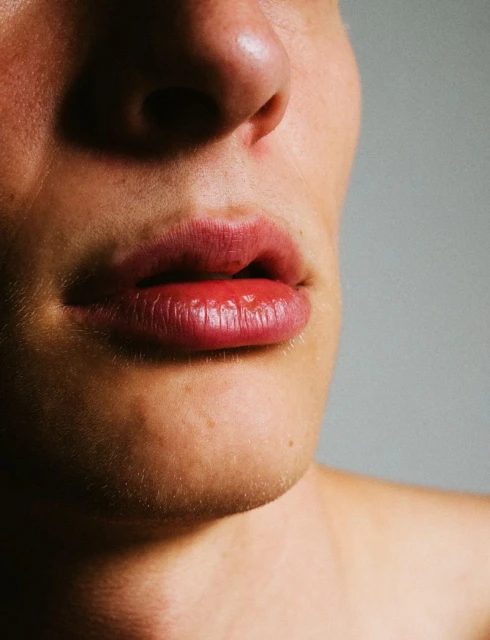 Close-up studio shot focuses on the face of an adult male, highlighting his lips, nose, and chin against a plain, light background.