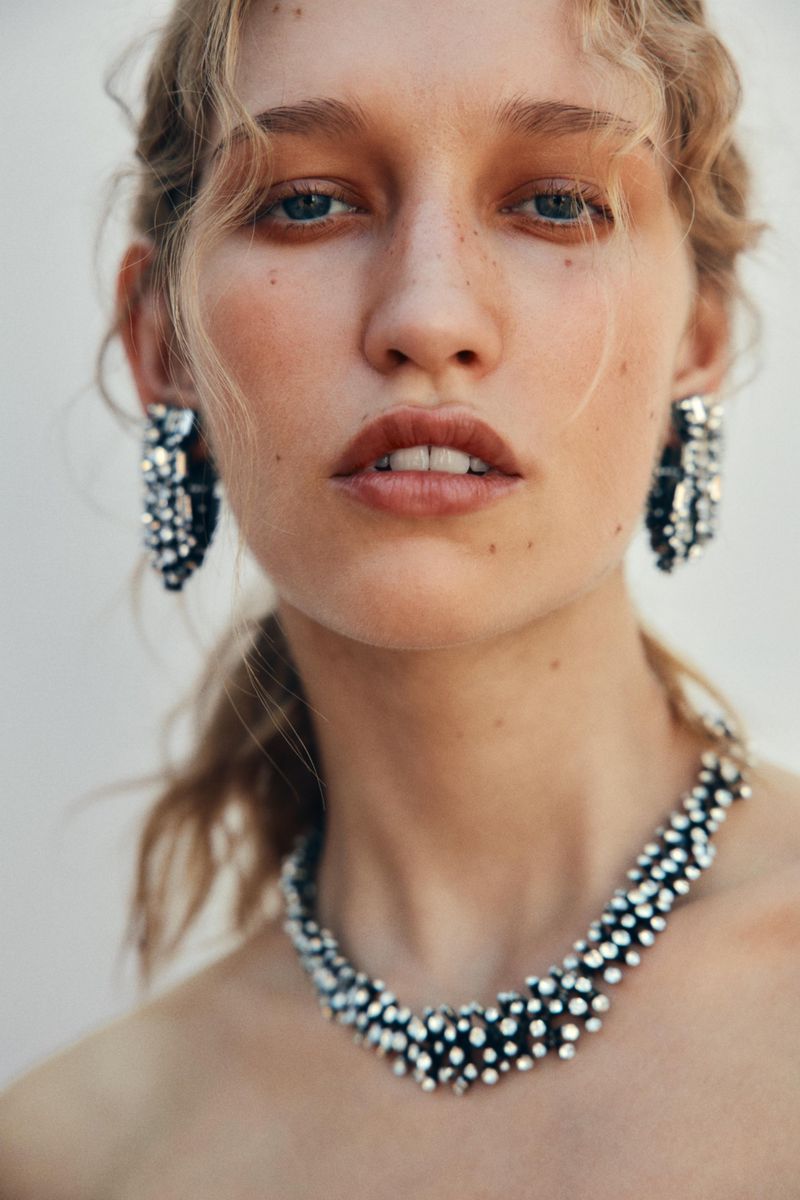 Model Apolline Rocco Fohrer wearing a textured silver crystal necklace and matching cluster earrings against a plain studio background.