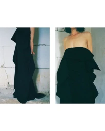 Model Akti Konstantinou in structured black strapless garment against a weathered wall for Crosscurrent project In Waiting