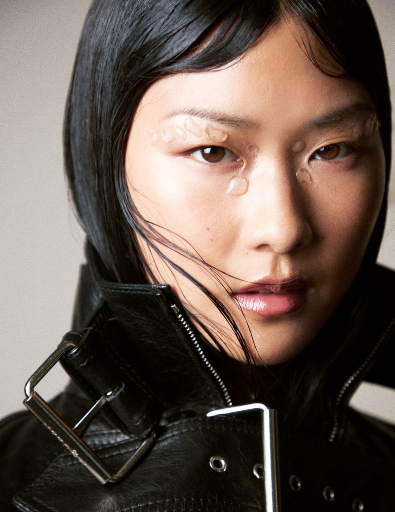 Close-up of a person with an East Asian appearance wearing a black leather jacket and adornments on the eyebrows.