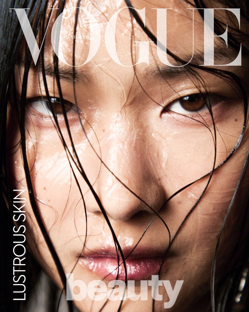 Close-up portrait of an Asian woman with wet hair and dewy skin, against a blurred background with Vogue magazine masthead and beauty text.
