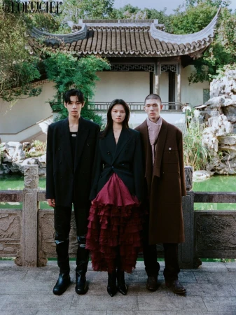 Three fashion models pose outdoors in front of a Chinese-style pavilion wearing dark-colored blazers and stylish outfits for a fashion shoot.