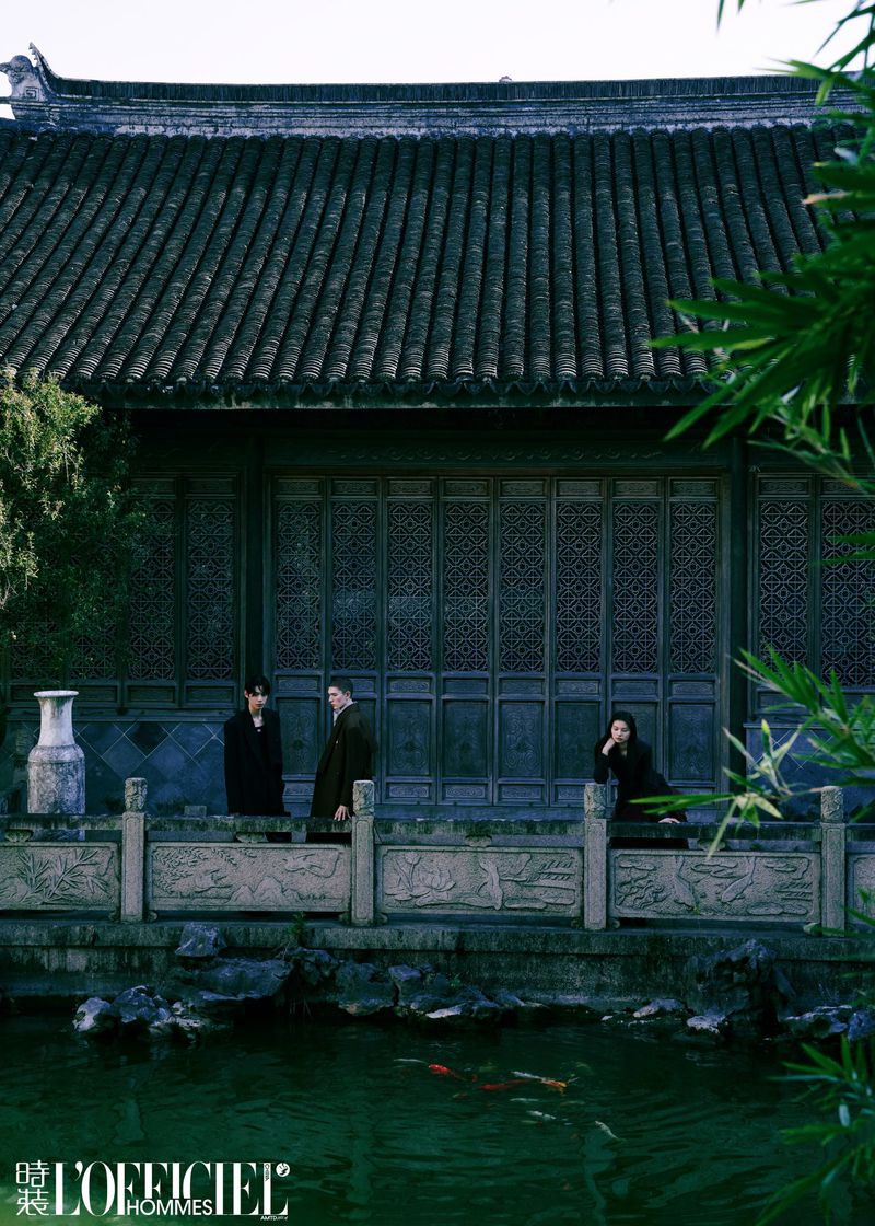 Three people stand in front of a traditional Chinese building with a pond featuring koi fish, captured in an editorial fashion shot.