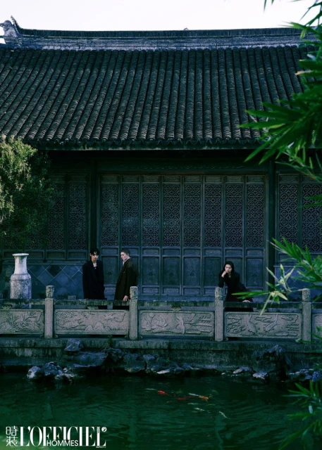 Three people stand in front of a traditional Chinese building with a pond featuring koi fish, captured in an editorial fashion shot.
