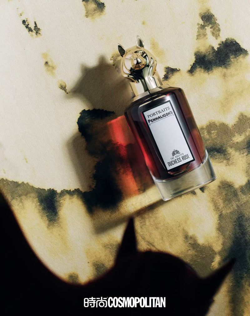 Penhaligon's Portraits Duchess Rose perfume bottle with a cat head cap on a marbled surface with a shadow. Beauty and personal care ad.