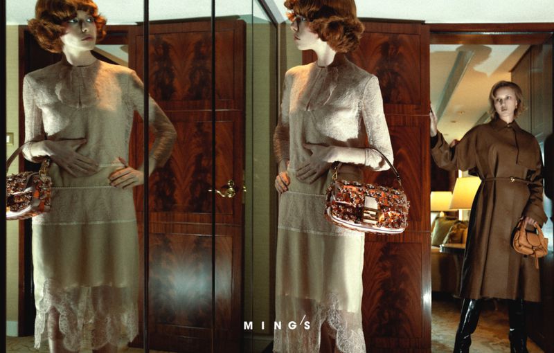 Fashion shot featuring a redhead fashion model posing with a handbag in an indoor environment with a vintage aesthetic and rich tones.
