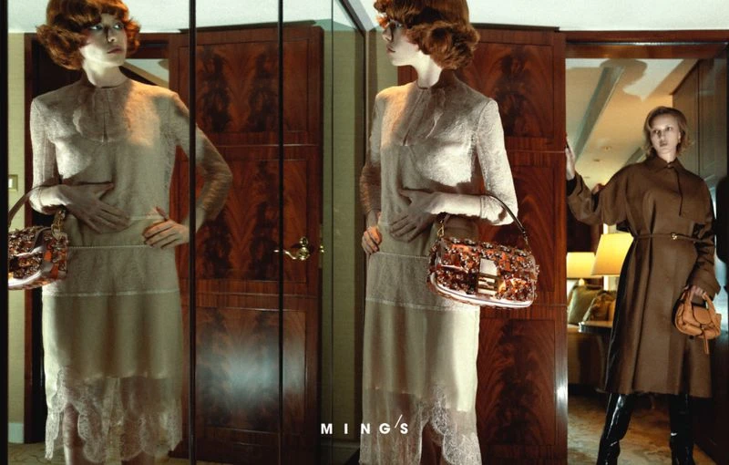 Fashion shot featuring a redhead fashion model posing with a handbag in an indoor environment with a vintage aesthetic and rich tones.