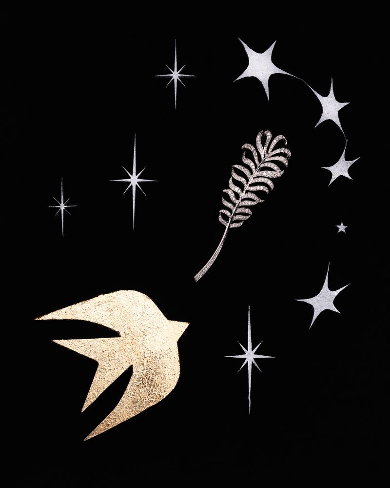 Illustration of a gold bird and silver feather surrounded by stars on a black backdrop, creating a celestial and decorative scene.