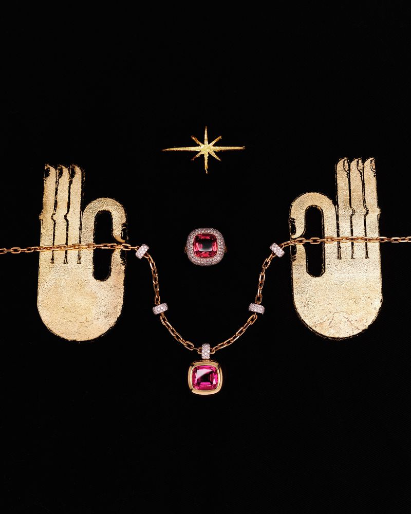 Elegant jewelry set on a black background featuring a necklace with a pink gemstone pendant and a matching pink gemstone ring.