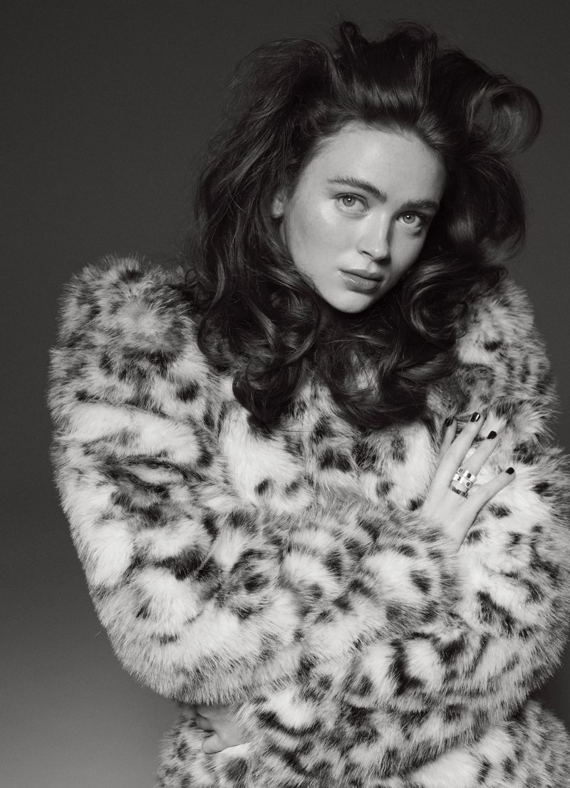 Monochrome portrait of a young woman in a patterned faux fur coat against a grey backdrop, showcasing fashion and beauty.