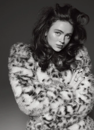 Monochrome portrait of a young woman in a patterned faux fur coat against a grey backdrop, showcasing fashion and beauty.