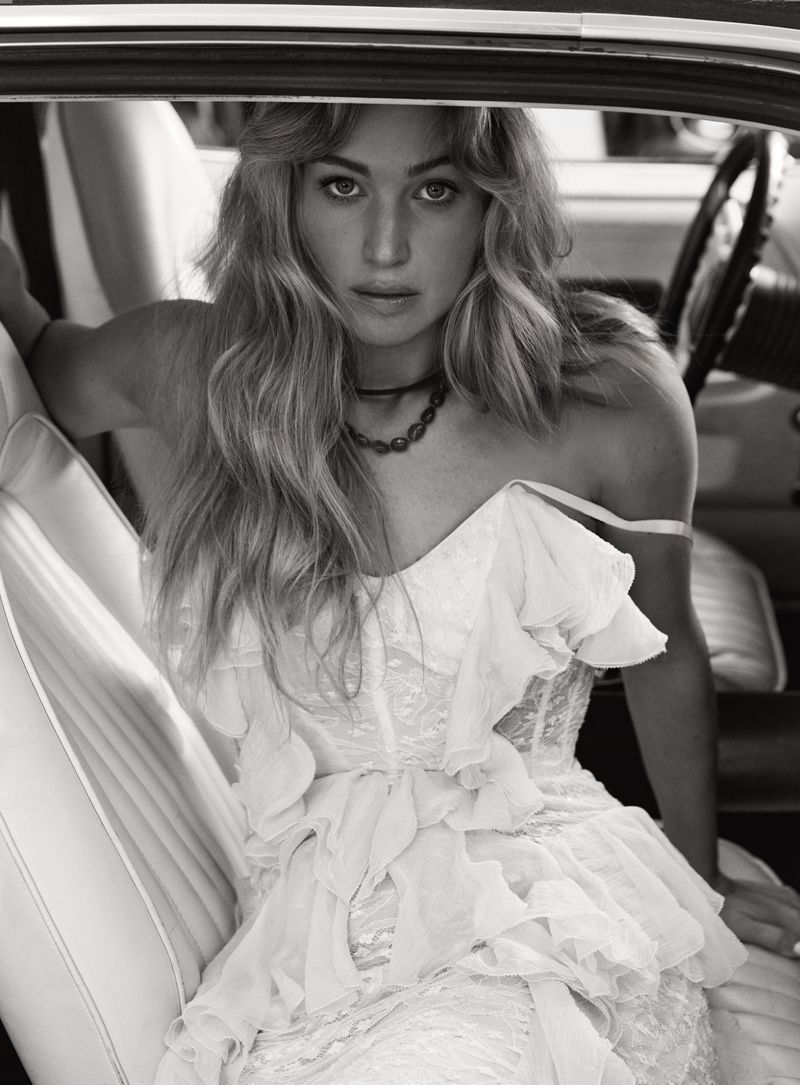 Jennifer Lawrence in a white lace dress seated inside a car for V Magazine, photographed by Cass Bird.